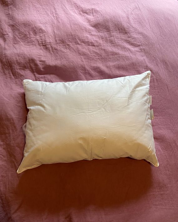 A white pillow on a pink duvet.