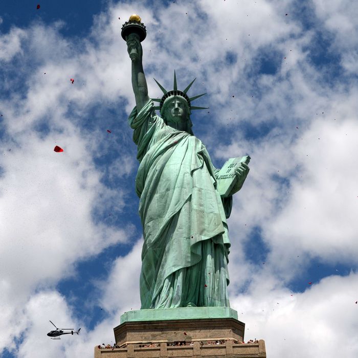 Rose petals are dropped from a helicopter on the Statue of Liberty June 6, 2014 on Liberty Island in New York. Thousands gathered on the island to participate in ceremonies commemorating the 70th anniversary of D-Day. Three helicopters dropped some one million rose petals in an sponsored by The French Will Never Forget. 