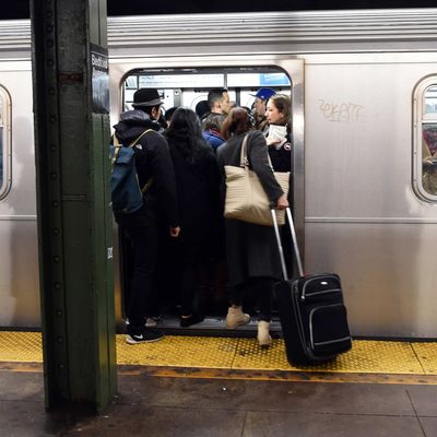 Commuters at the Bedford Ave subway station board a crowded train December 22, 2014 in New York. The last stop that the L train makes before traveling to Manhattan is said to be over-congested during the morning rush hour. 