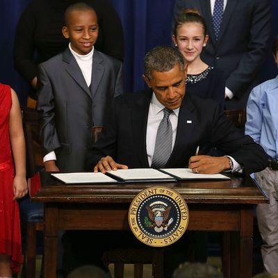  U.S. President Barack Obama is flanked by young children as he signs a executive order designed to tackle gun control, on January 16, 2012 in Washington, DC. One month after a massacre that left 20 school children and 6 adults dead in Newtown, Connecticut, the president unveiled a package of gun control proposals that include universal background checks and bans on assault weapons and high-capacity magazines. 