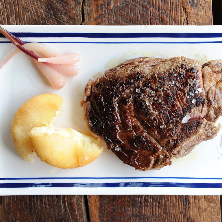 肋眼牛排配哥伦比亚式玉米饼和腌黄瓜。