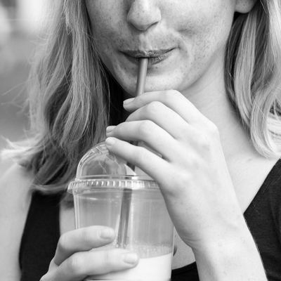 Blonde woman drinking from a plastic straw.