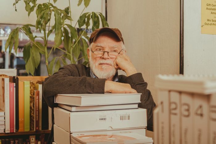 Store owner Nach Waxman sitting at a desk, leaning on a pile of books.