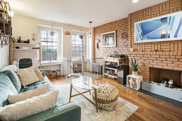 Living room with two windows and a wall of exposed brick.