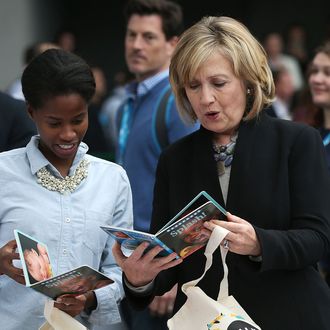 SAN FRANCISCO, CA - OCTOBER 14: Former U.S. Secretary of State Hillary Clinton (R) inspects a book as she helps assemble bags for the Clinton Foundation's Too Small to Fail program during the 2014 DreamForce conference on October 14, 2014 in San Francisco, California. The annual Dreamforce conference runs through October 16. (Photo by Justin Sullivan/Getty Images)