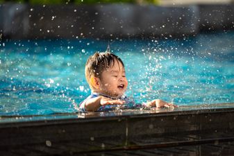 Vietnamese - Happy child playing with water splashes in the pool