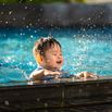 Vietnamese - Happy child playing with water splashes in the pool
