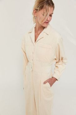 BDG Hans Corduroy Coverall Jumpsuit soft cream cashmere sweater with a subtle black pattern and high waisted black jeans on a model with red curly hair. The Strategist - 