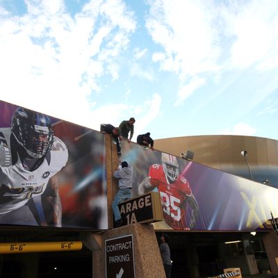 Workers install signs at the Mercedes-Benz Superdome prior to Super Bowl XLVII on January 31, 2013 in New Orleans, Louisiana.