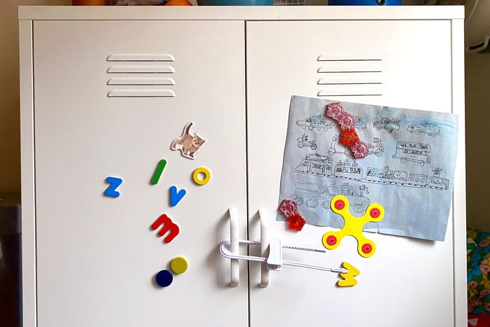 Photo of a metal cabinet with a Safety 1st baby proofing slide lock installed across its two doors.