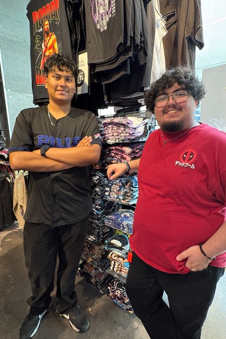 Two boys posing next to a display of wrestling shirts. 