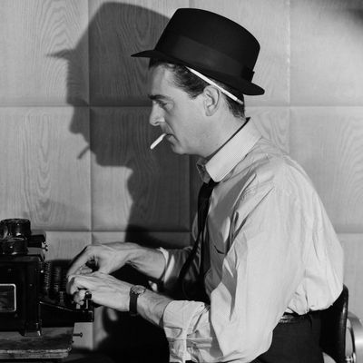 Newspaper reporter at typewriter smoking a cigarette. Undated photograph. --- Image by ? Bettmann/CORBIS