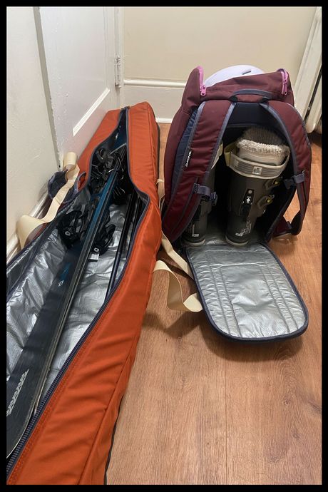 An open ski bag and boot bag, with skis and boots inside.
