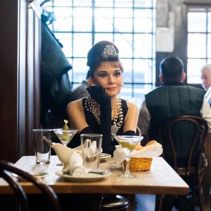 A wax sculpture of Audrey Hepburn in breakfast at Tiffany's dress sitting at Peter Luger's, a steakhouse in Brooklyn.