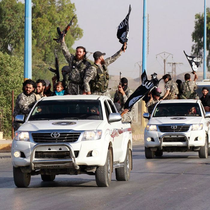 Militant Islamist fighters wave flags as they take part in a military parade along the streets of Raqqa