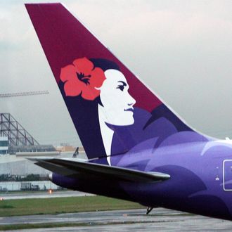 A worker stands next to the tail of a Hawaiian Airlines aircraft parked at Manila international airport on June 16, 2008. AFP PHOTO/TED ALJIBE (Photo credit should read TED ALJIBE/AFP/Getty Images)