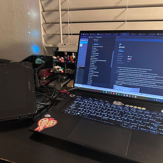 A drawing tablet and a computer with writing software open sit on a desk.