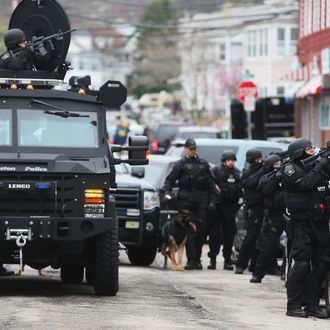 WATERTOWN, MA - APRIL 19: SWAT team members aim their guns as they search for one remaining suspect at an apartment building on April 19, 2013 in Watertown, Massachusetts. Earlier, a Massachusetts Institute of Technology campus police officer was shot and killed at the school's campus in Cambridge. A short time later, police reported exchanging gunfire with alleged carjackers in Watertown, a city near Cambridge. According to reports, one suspect has been killed during a car chase and the police are seeking another - believed to be the same person (known as Suspect Two) wanted in connection with the deadly bombing at the Boston Marathon earlier this week. Police have confirmed that the dead assailant is Suspect One from the recently released marathon bombing photographs. (Photo by Mario Tama/Getty Images)