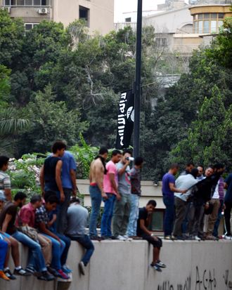 Egyptian protesters raise inside the US embassy a black flag inscribed with the Muslim profession of belief: 