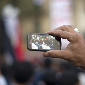 A man uses his a cellphone to record the activity of fellow pro-reform protestors during a massive demonstration in Cairo's Tahrir square on November 24, 2011. Members of Egypt's ruling military council rejected calls to step down immediately, saying it would amount to a 