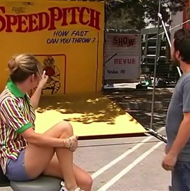 Charlie can't read the "SpeedPitch" sign at the fair.
