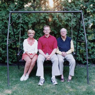 Mature couple and son sitting on lawn swing.