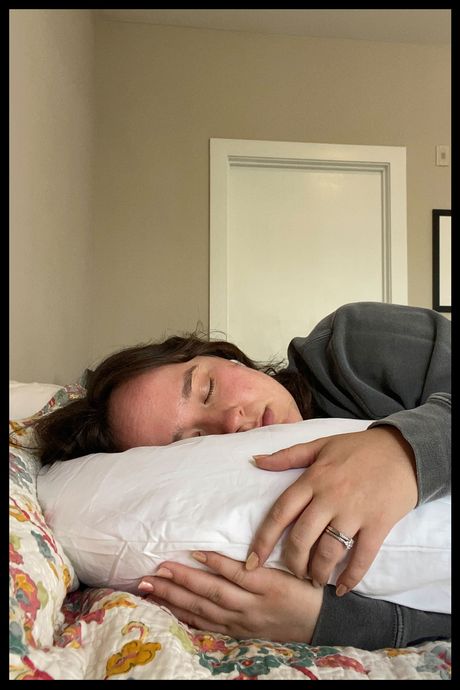 A woman sleeping on her side while hugging a pillow in front of her.