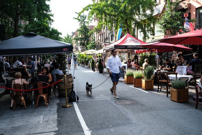 People eating and drinking at outdoor restaurants on a summer day in one of New York City's Open Streets