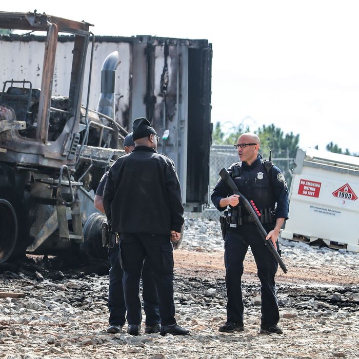 Georgia law-enforcement officers in front of a charred construction vehicle in the South River Forest.