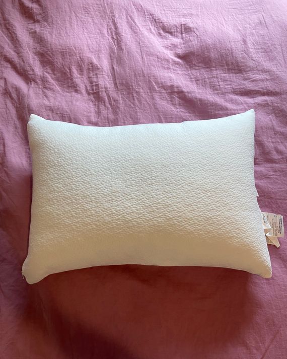 A white pillow on a pink duvet.