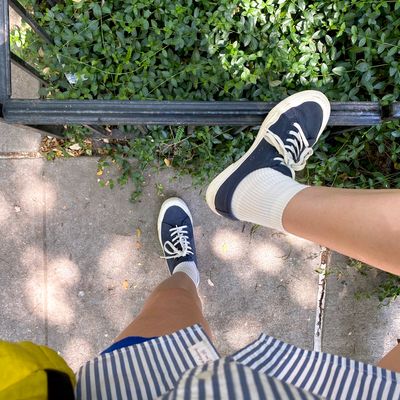 View looking down at a pair of feet in Seavees sneakers and a pair of white ribbed Bombas quarter socks. 