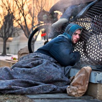 Nick warms himself on a steam grate with three other homeless men by the Federal Trade Commission, just blocks from the Capitol, during frigid temperatures in Washington, Saturday, Jan. 4, 2014. A winter storm that swept across the Midwest this week blew through the Northeast on Friday, leaving bone-chilling cold in its wake. (AP Photo/Jacquelyn Martin)