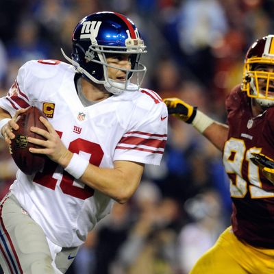 Quarterback Eli Manning #10 of the New York Giants scrambles as he is being chased by Ryan Kerrigan #91 of the Washington Redskins in the third quarter against the Washington Redskins at FedExField on December 3, 2012 in Landover, Maryland.