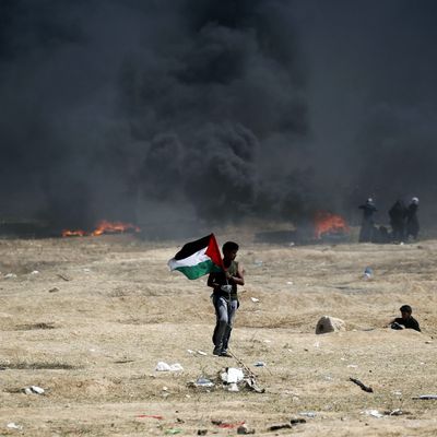 A man holds a Palestinian flag during clashes with Israeli forces near the border between the Gaza strip and Israel, east of Gaza City on May 14, 2018, following the the controversial move to Jerusalem of the United States embassy.