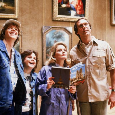 Medium shot of Jason Lively as Russell 'Rusty' Griswald wearing hat, Dana Hill as Audrey Griswald, Beverly D'Angelo as Ellen Griswald holding book and Chevy Chase as Clark Griswald wearing glasses. 