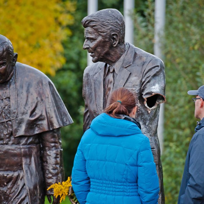 In this Oct. 1, 2013 photo passersbys are seen looking at a former president Ronald Reagan statue with a severed arm in a park in Gdansk, Poland. The bronze statue is a larger than life rendering of Reagan and the Polish born Pope John Paul II, inspired by an AP photograph taken by Scott Stewart during John Paul's visit to the US in 1987 and honor's Reagan's support for Poland's struggle to end communism. The police are searching for the vandal who cut the arm off. (AP Photo/Mateusz Ochocki)