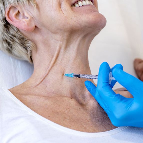 Closeup of a cheerful old female getting neck botox in a hospital