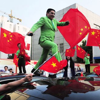 This picture taken on October 10, 2012 shows Chinese billionaire and philanthropist Chen Guangbiao jumping on the roofs of the new cars which he bought costing five million yuan (795,000 USD) in Beijing as presents to the 43 owners of Japanese cars that were damaged last month during the nationwide anti-Japan protests that were fueled by Japan's 