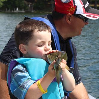 In this photo made Wednesday, June 26, 2013 in Nevis , Minn., Bobby Tufts, the 4-year-old mayor of Dorset, Minn., kisses a fish that his guide, Jason Durham, caught on Lake Belle Taine. The fish, the first was released. Bobby was only 3 when he won election last year as mayor of Dorset (population 22 to 28, depending on whether the minister and his family are in town). Dorset, which bills itself as the Restaurant Capital of the World, has no formal city government. 