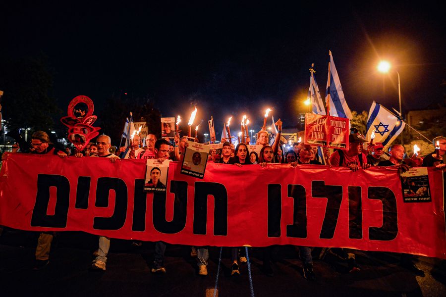 Families of the Israeli hostages march with a banner,