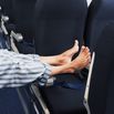 Man lying on aeroplane seats, legs stretched across aisle, low section