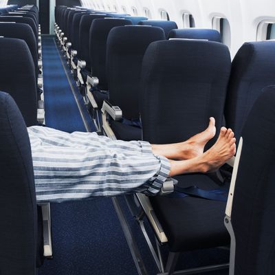 Man lying on aeroplane seats, legs stretched across aisle, low section