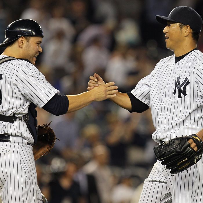 Hiroki Kuroda #18 of the New York Yankees celebrates with Russell Martin #55 after pitching a complete game shutout against the Texas Rangers at Yankee Stadium on August 14, 2012 in the Bronx borough of New York City. Yankees defeated the Rangers 3-0.