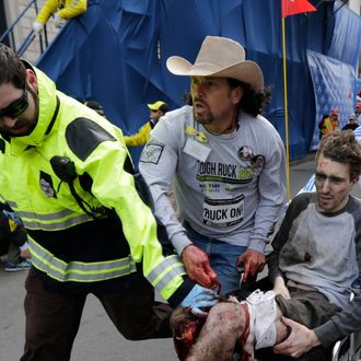 FILE - In this April 15, 2013 file photo, an emergency responder and volunteers, including Carlos Arredondo, in the cowboy hat, push Jeff Bauman in a wheel chair after he was injured in an explosion near the finish line of the Boston Marathon. At least three people were killed, including an 8-year-old boy, and more than 170 were wounded when two bombs blew up seconds apart. Virtually overnight, Arredondo, a peace activist and sometime cabbie taxi and truck driver, has turned into a living reminder of both the horror and bravery witnessed in Monday’s double bombing at the finish line of the race. (AP Photo/Charles Krupa, File)