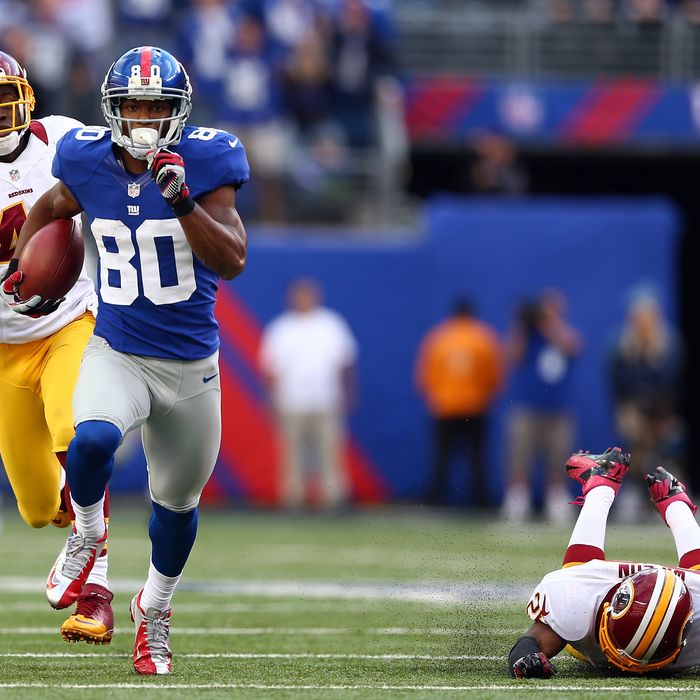 Victor Cruz #80 of the New York Giants carries the ball past Madieu Williams #41 and Josh Wilson #26 of the Washington Redskins to score the game winning touchdown on October 21, 2012 at MetLife Stadium in East Rutherford, New Jersey.The New York Giants defeated the Washington Redskins 27-23.