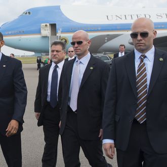 US President Barack Obama (L), surrounded by US Secret Service agents, walks to greet guests upon arrival on Air Force One at Tampa International Airport in Tampa, Florida, on April 13, 2012. Obama arrived in Tampa to speak at the Port of Tampa, before continuing to the Summit of the Americas in the Colombian city of Cartagena. AFP PHOTO/Saul LOEB (Photo credit should read SAUL LOEB/AFP/Getty Images)