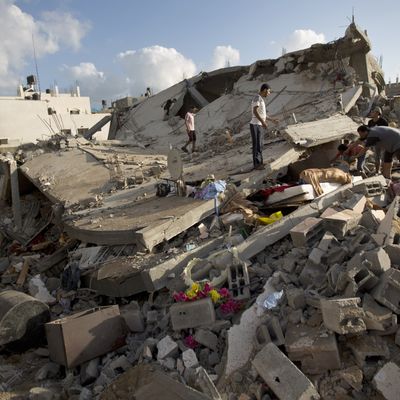 Palestinian men rescue items from a destroyed building following an Israeli military strike on Beit Lahya, northern Gaza Strip on July 15, 2014. Israel's security cabinet on Tuesday accepted an Egyptian ceasefire proposal after a week of the deadliest violence in and around Gaza in years, Israeli media reports said. AFP PHOTO/MAHMUD HAMS (Photo credit should read MAHMUD HAMS/AFP/Getty Images)