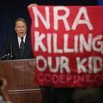A demonstrator from CodePink holds up a banner as National Rifle Association Executive Vice President Wayne LaPierre delivers remarks during a news conference at the Willard Hotel December 21, 2012 in Washington, DC. This is the first public appearance that leaders of the gun rights group have made since a 20-year-old man used a popular assault-style rifle to slaughter 20 school children and six adults at Sandy Hook Elementary School in Newtown, Connecticut, one week ago.