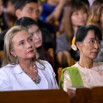 YANGON, MYANMAR - NOVEMBER 19: US Secretary of State Hilary Clinton (L) listens alongside Aung San Suu Kyi as US President Barack Obama speaks at the University of Yangon during his historical first visit to the country on November 19, 2012 in Yangon, Myanmar. Obama is the first US President to visit Myanmar while on a four-day tour of Southeast Asia that also includes Thailand and Cambodia. (Photo by Paula Bronstein/Getty Images)