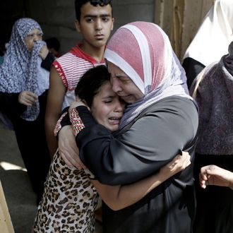 The young daughter (L) of Hasan Baker, 60-years-old, is comforted during his funeral of her Gaza City, on July 22, 2014. A series of Israeli air strikes early killed seven people in Gaza, including five members of the same family, emergency services spokesman Ashraf al-Qudra said. The deaths hike the total Palestinian toll to 583 since the Israeli military launched Operation Protective Edge on July 8 in a bid to stamp out rocket fire from Gaza. AFP PHOTO / MOHAMMED ABED (Photo credit should read MOHAMMED ABED/AFP/Getty Images)